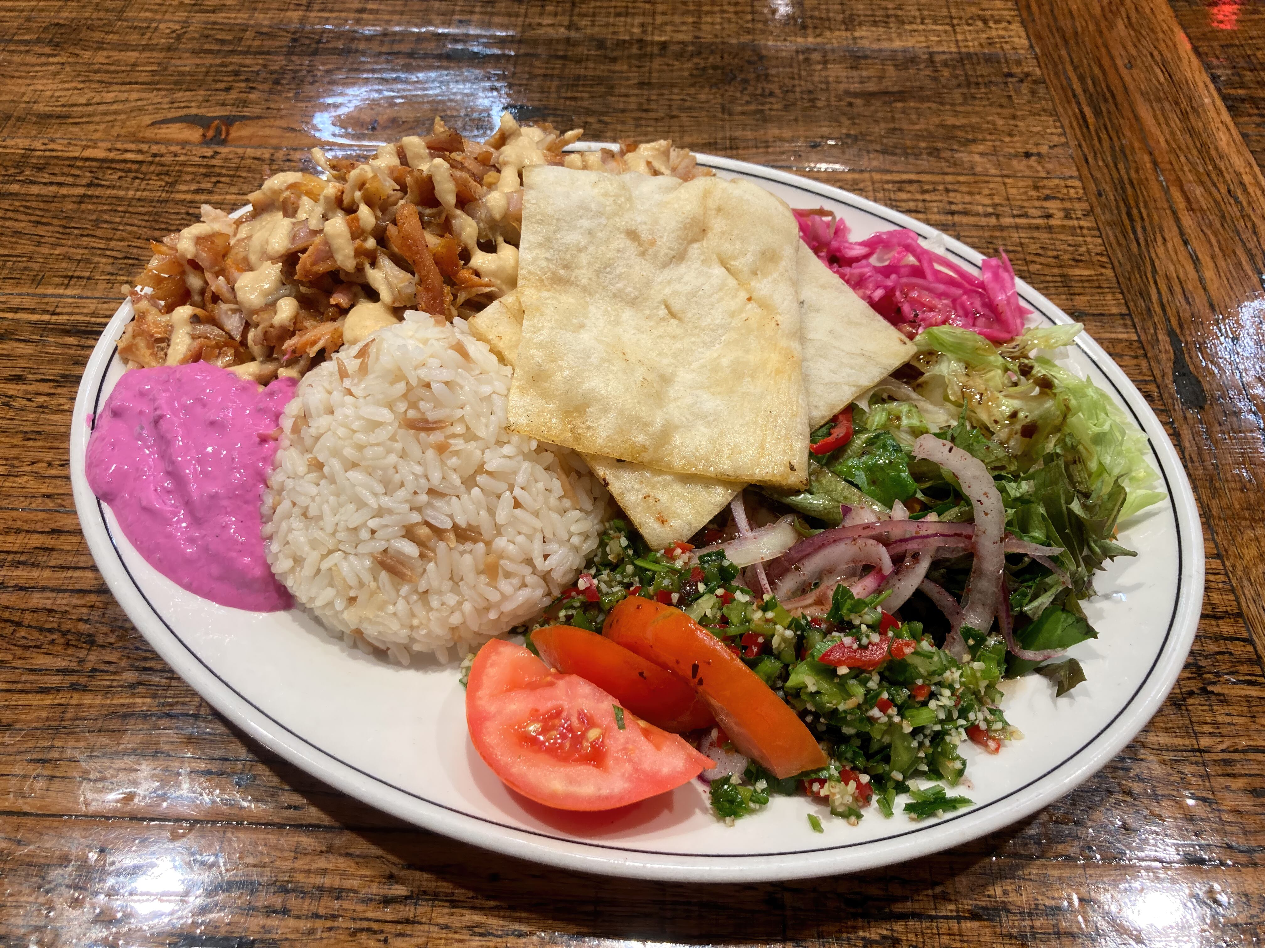 Plato de kebab de pollo con pan turco, arroz con pasta, ensaladas, salsa de hummus y remolacha. Getty Images.