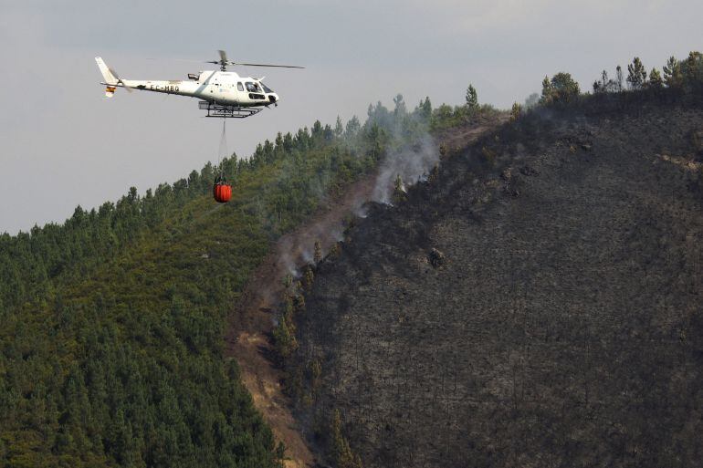 Un helicóptero durante las labores de extinción del incendio forestal declarado ayer en la parroquia de San Tomé, en Cervantes, que afecta a una superficie de más de 30 hectáreas. EFE-Eliseo Trigo