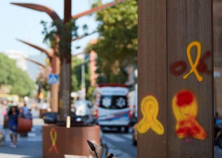 Unos vecinos del barrio pasan ante unos lazos amarillos en el barrio de Sants de Barcelona