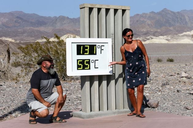 Una pareja de turistas posa frente al termómetro que marca 55 grados.