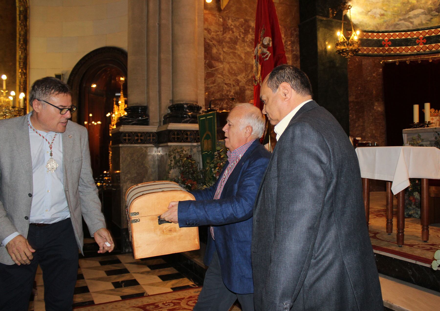 El presidente de la Asociación de San Jorge traslada el cofre con la ayuda de los ponentes de Mayorales