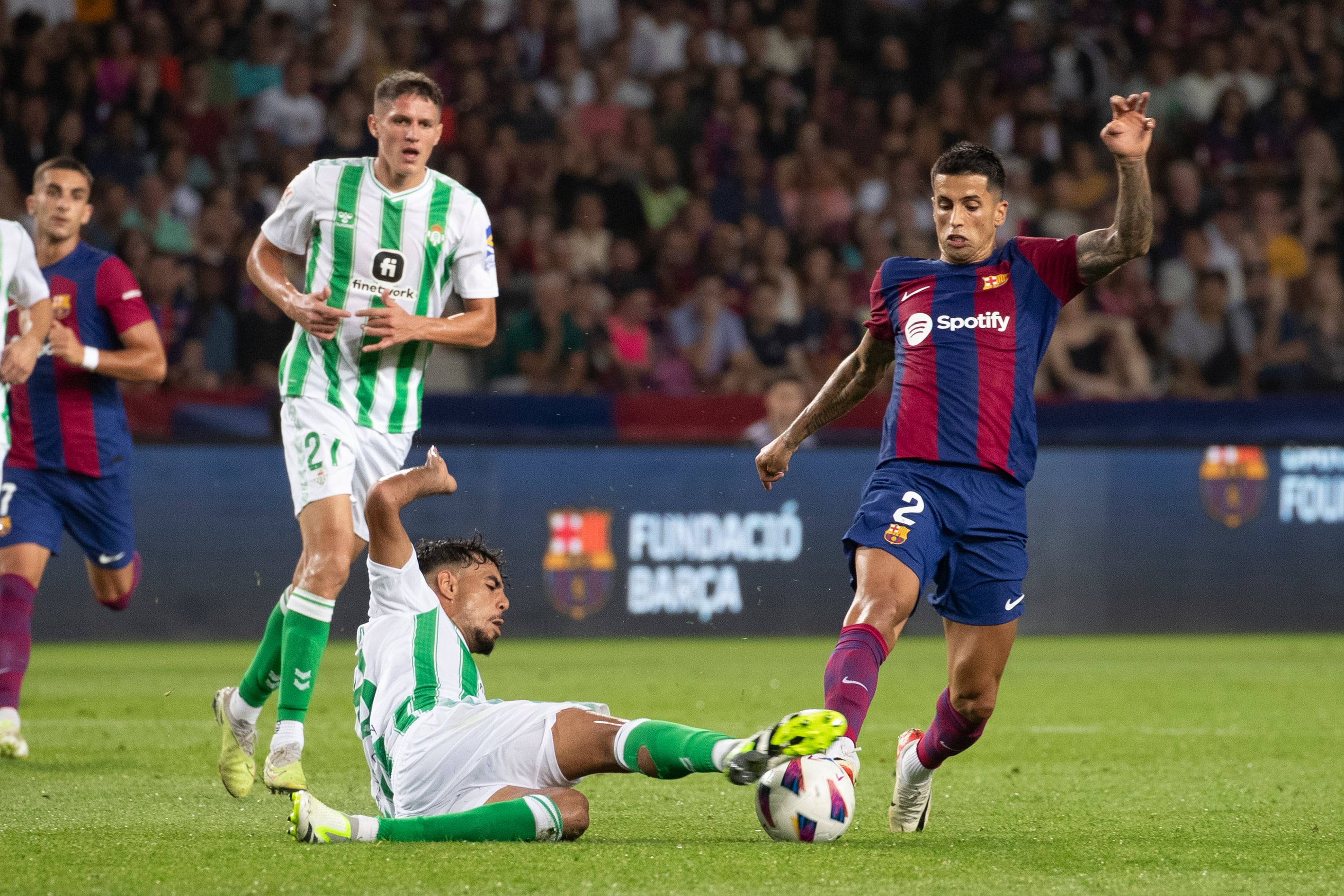 BARCELONA, 16/09/2023.- El defensa del FC Barcelona, João Cancelo (d) disputa una posesión ante Chadi Riad, (c) defensa marroquí del Real Betis durante el encuentro correspondiente a la quinta jornada de primera división que disputan hoy sábado en el estadio Olímpico de Montjuic, en Barcelona. EFE / Marta Pérez.
