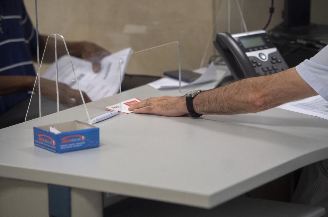 Un empleado atiende a una persona en su puesto de trabajo.