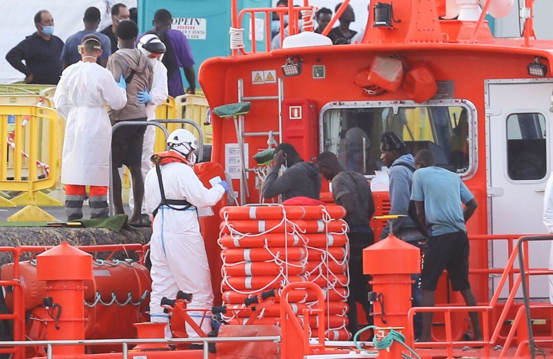 El personal de Salvamento Marítimo ayuda a los inmigrantes a desembarcar en el puerto de Arguineguín (Gran Canaria)