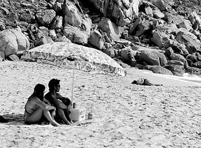 Una pareja de bañistas observa indiferente el cadáver de un inmigrante ahogado tras el naufragio de su patera (JAVIER BAULUZ).