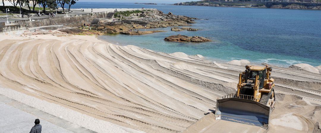 Máquina excavadora retira la duna en la playa del Riazor