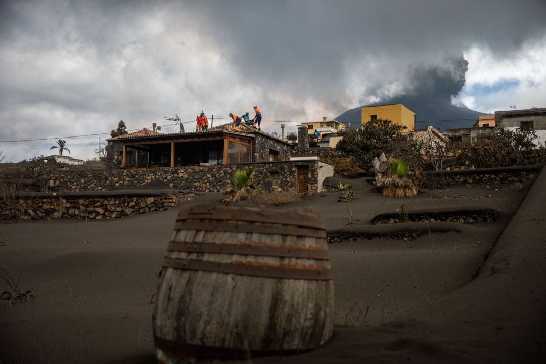 Varios voluntarios trabajan retirando cenizas de los tejados de varias casas próximas al volcán de Cumbre Vieja, a 5 de noviembre de 2021, en La Palma, Canarias (España).