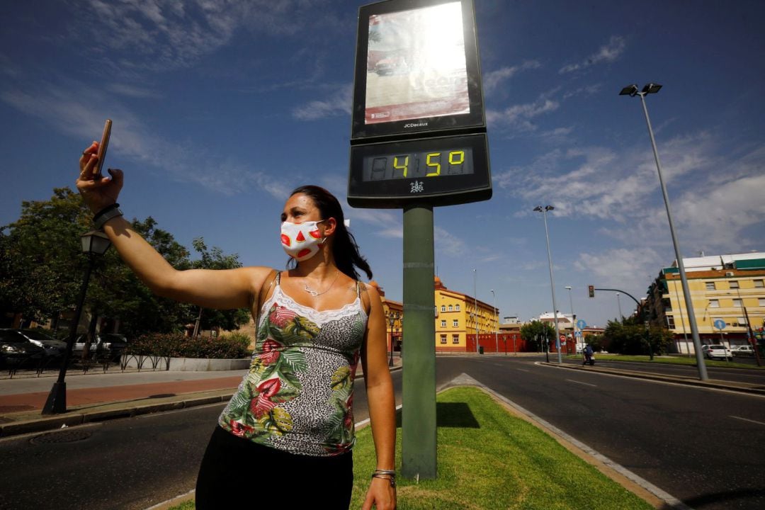 Una mujer se hace una foto junto a un termómetro que marca los 45 grados en las calles de Córdoba este sábado