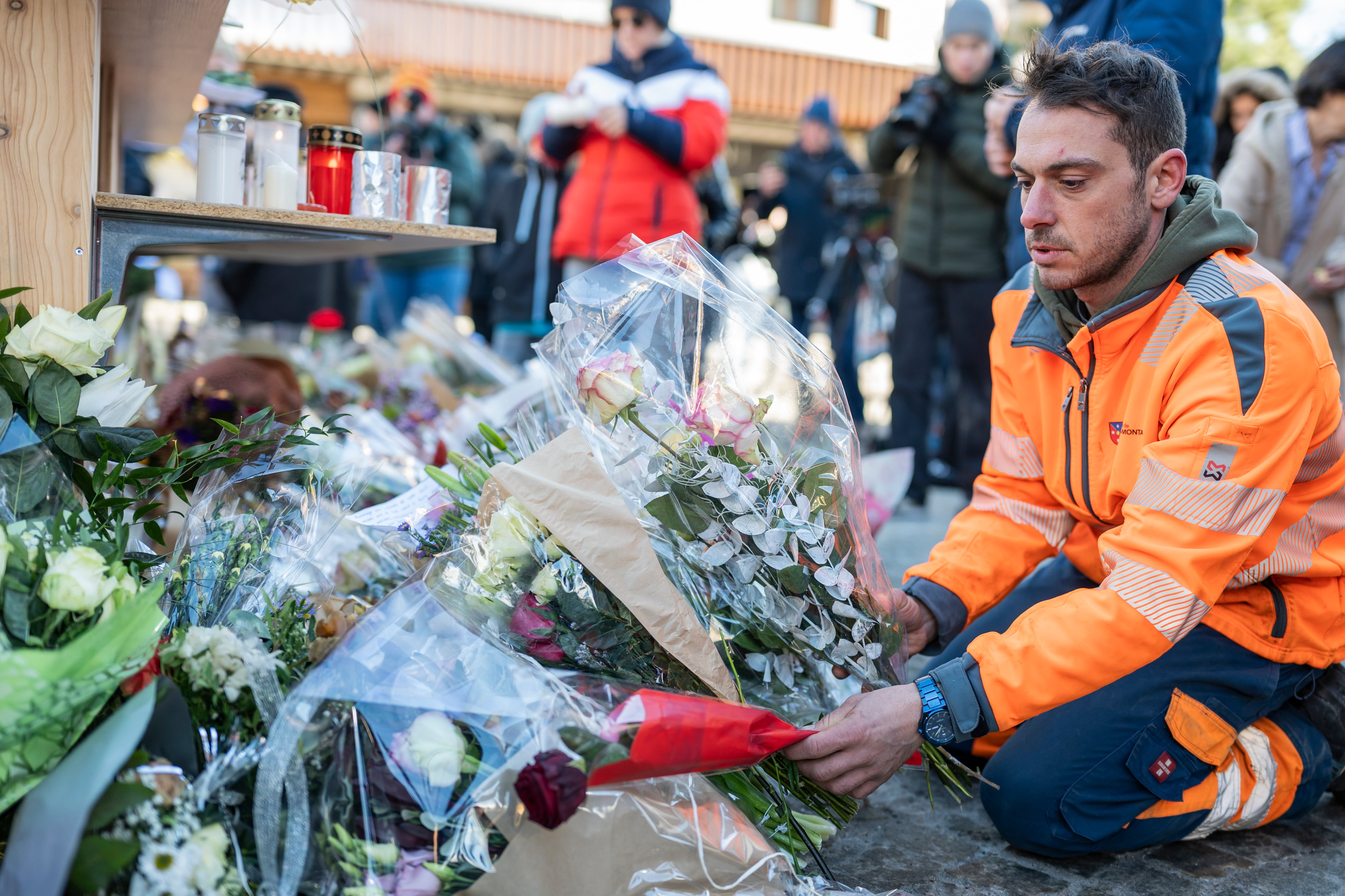 Un trabajador de Crans-Montana deposita un ramo de flores en el lugar de la tragedia