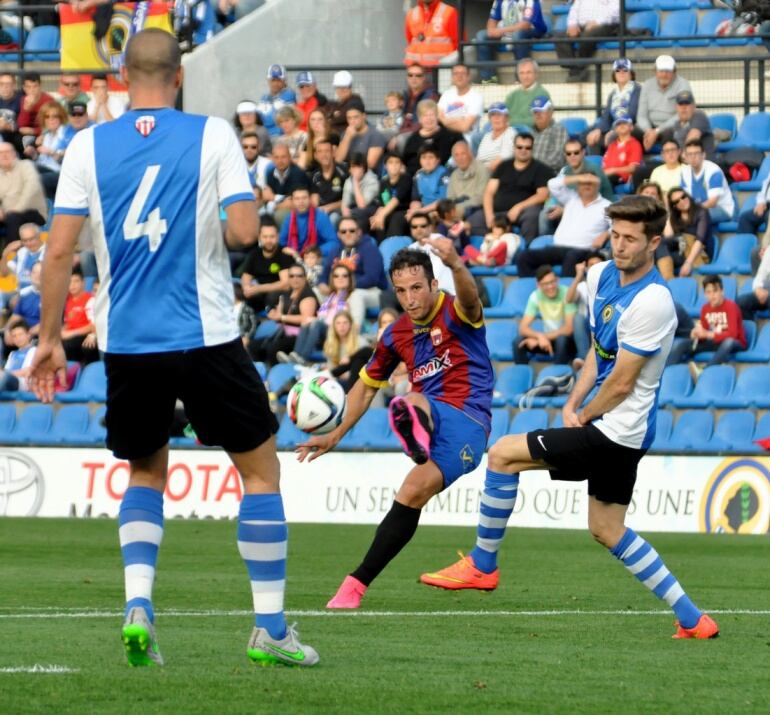 Piquero chutando entre dos futbolistas del Hércules