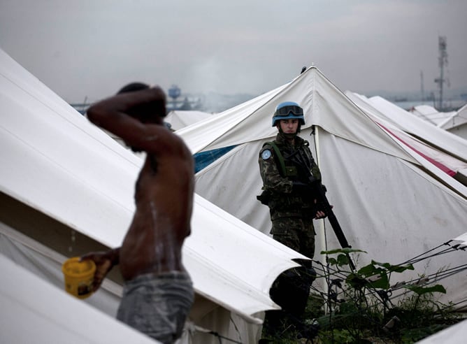 Un soldado observa a un hombre lavándose en un campo de desplazados de Cite Soleil, Puerto Príncipe (Haití)