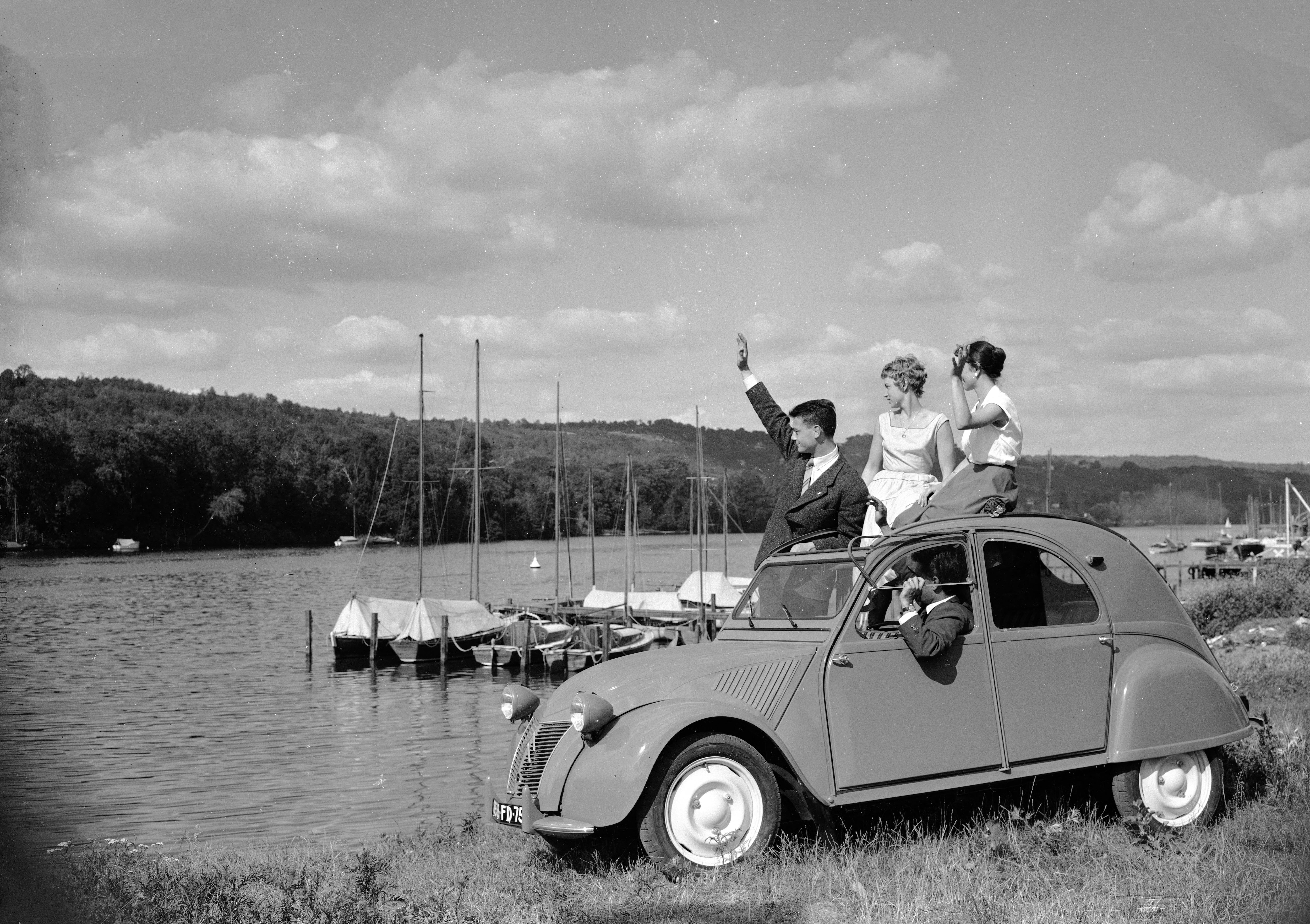 Europa, Francia, Isla de Francia, Yvelines, Meulan-en-Yvelines. Mujeres y hombres dentro y fuera de un 2CV estacionado junto al puerto en 1956.