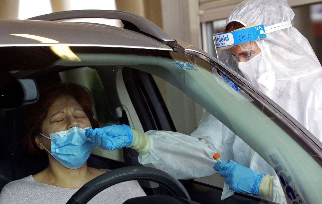 En la imagen una sanitaria protegida con EPI toma una muestra para una prueba PCR frente al hospital de Gandía