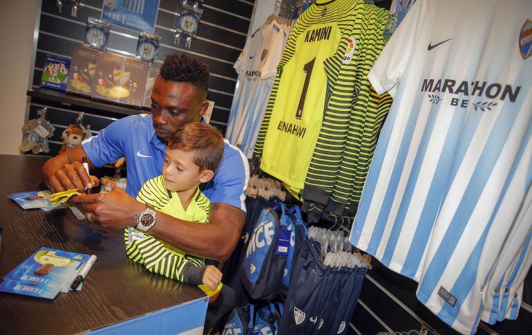 Kameni le firma un autógrafo a un niño en la tienda del Málaga en Fuengirola