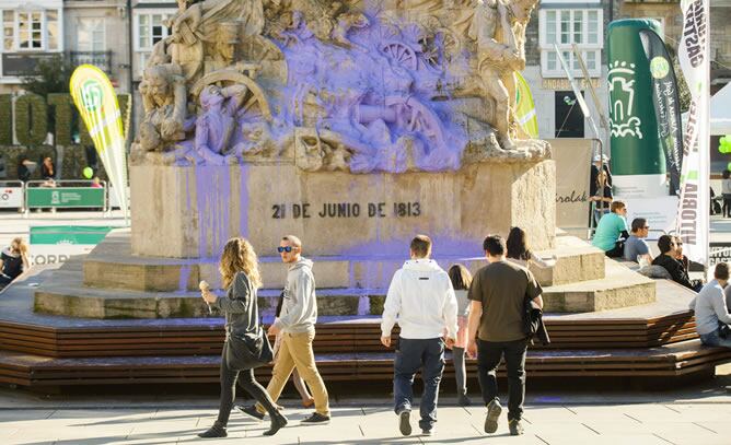 Varias personas ante el monumento a la Batalla de Vitoria, ubicado en la plaza de la Virgen Blanca de la capital alavesa, que se encontraba cubierto de pintura de lila después de que varios jóvenes lanzasen botes de contra él