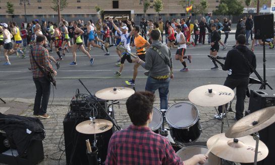 orredores del XXXII Maratón de Sevilla pasan junto a la actuación de un grupo musical