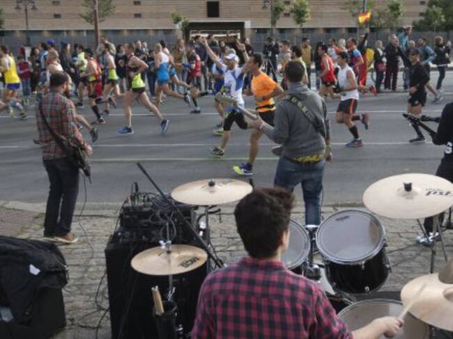 orredores del XXXII Maratón de Sevilla pasan junto a la actuación de un grupo musical
