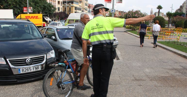 Un agente cívico de Girona informa a un ciclista 