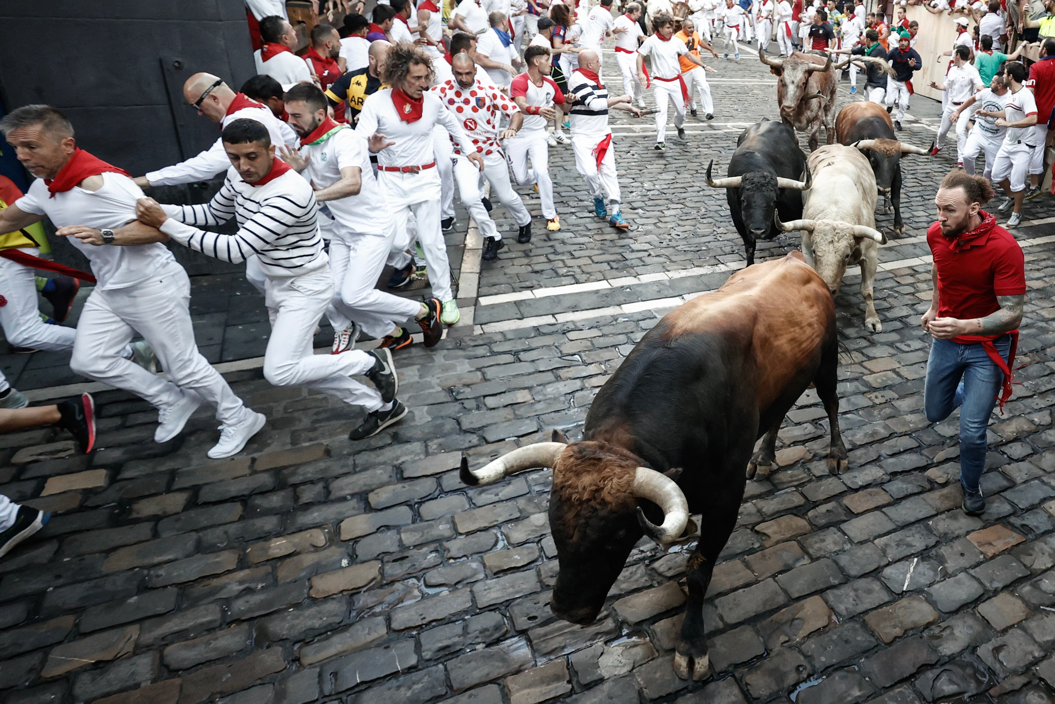 Los toros de la ganadería de Fuente Ymbro a su paso por la curva de Mercaderes durante el cuarto encierro de los sanfermines 2023