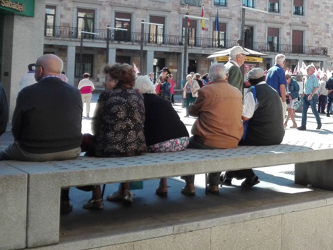 Personas mayores sentadas en un banco de la Plaza de la Constitución de la capital