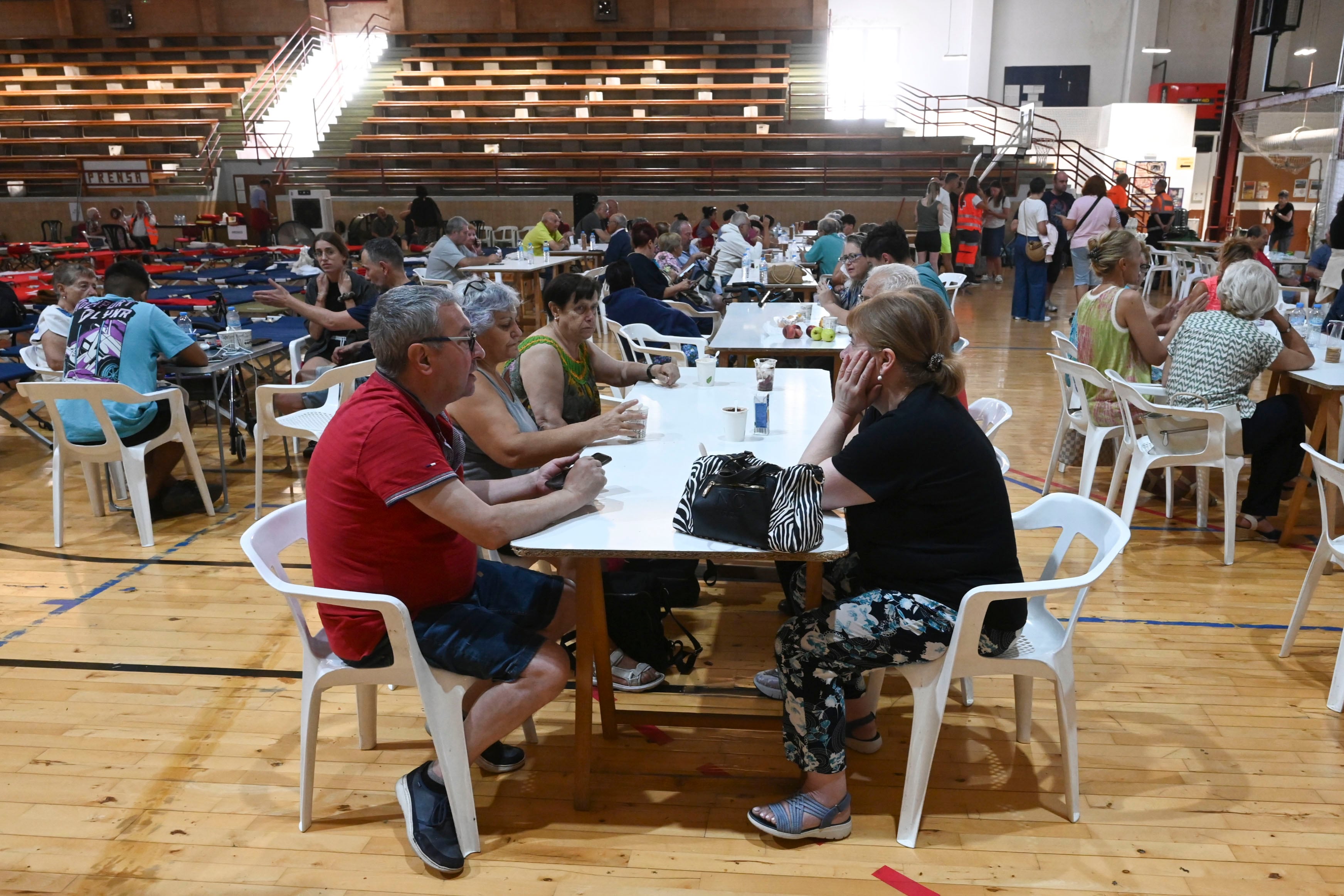LA BAÑEZA (LEÓN), 13/08/2025.- Personas desalojadas de sus viviendas en el pabellón municipal de La Bañeza, en el que se han habilitado 235 camas para vecinos desplazados por los incendios. Cruz Roja León ha habilitado un total de 715 camas en distintas instalaciones de Astorga, La Bañeza y Ponferrada para alojar a parte de los vecinos de las localidades evacuadas por los incendios que asolan el sureste de la provincia leonesa y a brigadistas que trabajan contra las llamas en El Bierzo.EFE/J.Casares