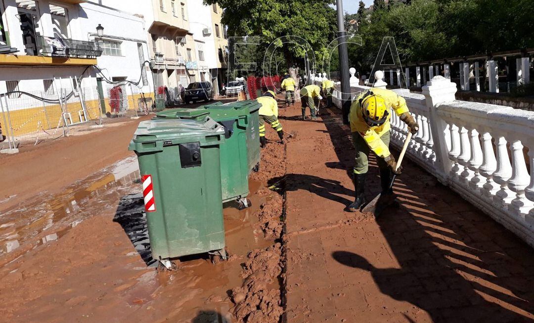 Dos bomberos del Plan Infoca limpian las calles de Beas de Segura después de la riada del 10 de septiembre.