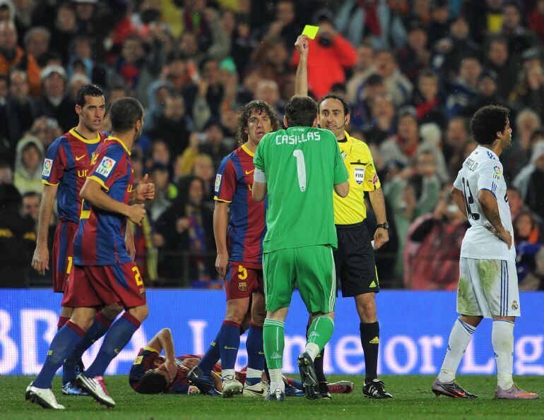 Iturralde enseña la tarjeta amarilla a Casillas durante un Clásico