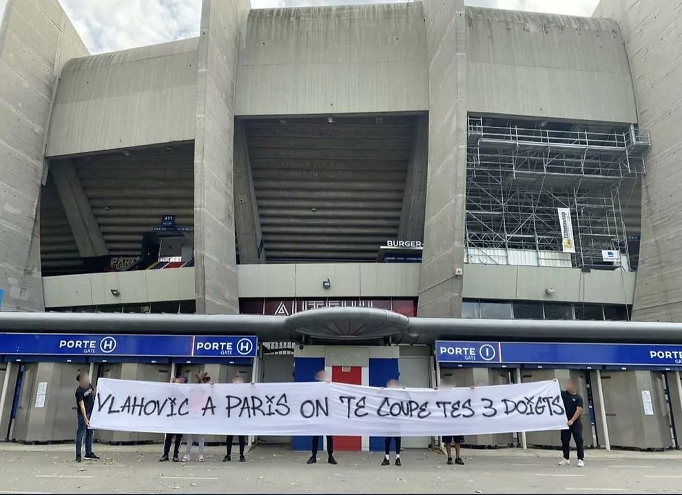 Los ultras del PSG sujetando una pancarta donde se lee una amenaza a Vlahovic en las inmediaciones del estadio del conjunto parisino.