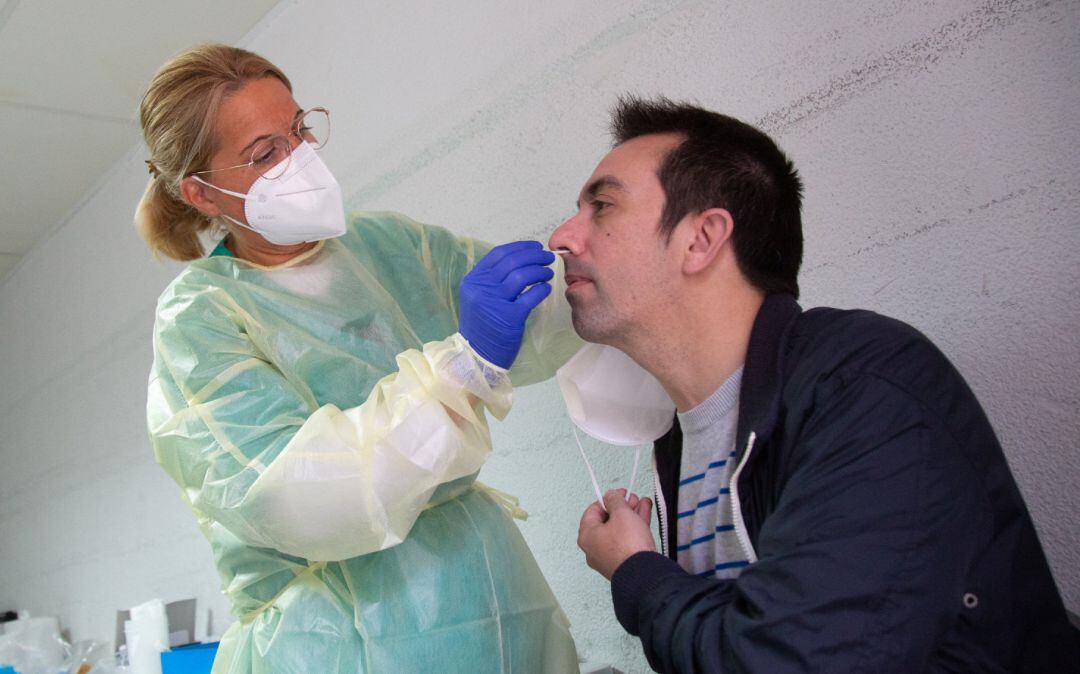 Una sanitaria realiza un test de antígenos o una PCR a un hombre.