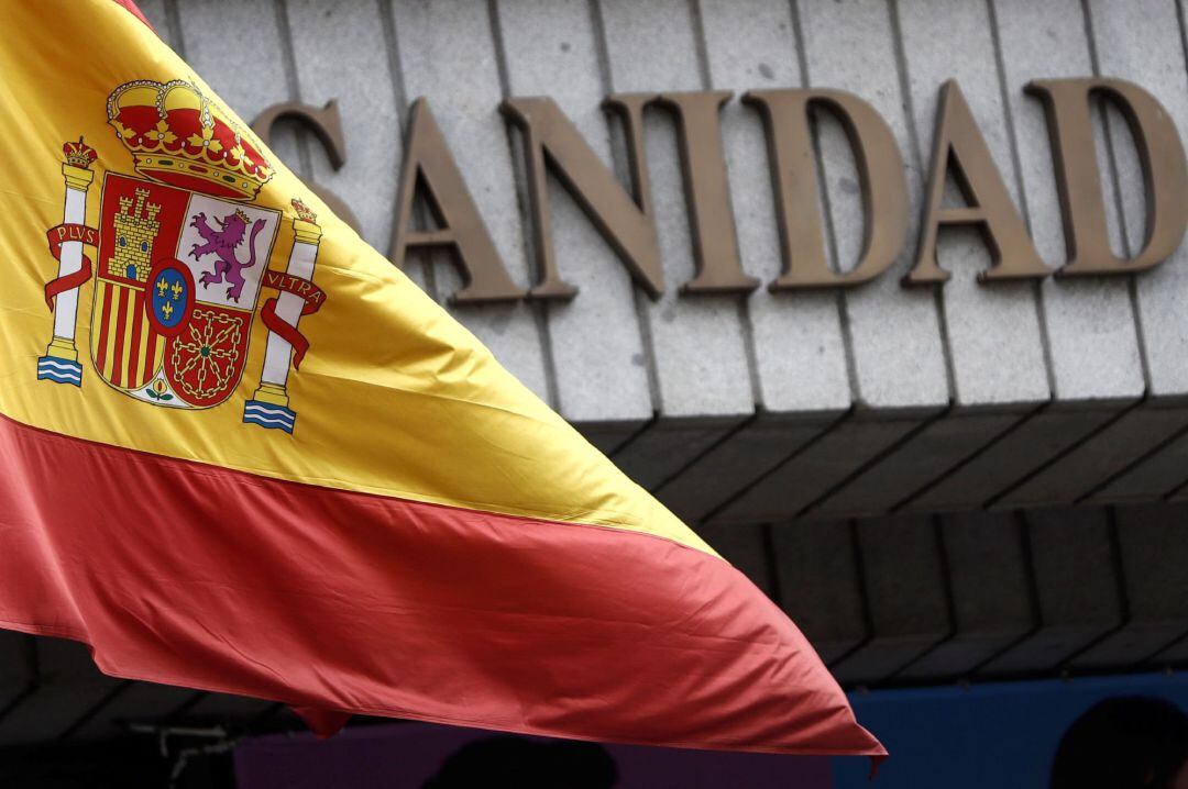 Una bandera española ondea en la fachada del Ministerio de Sanidad y Consumo, que permanece este lunes custodiado por efectivos de la Guardia Civil