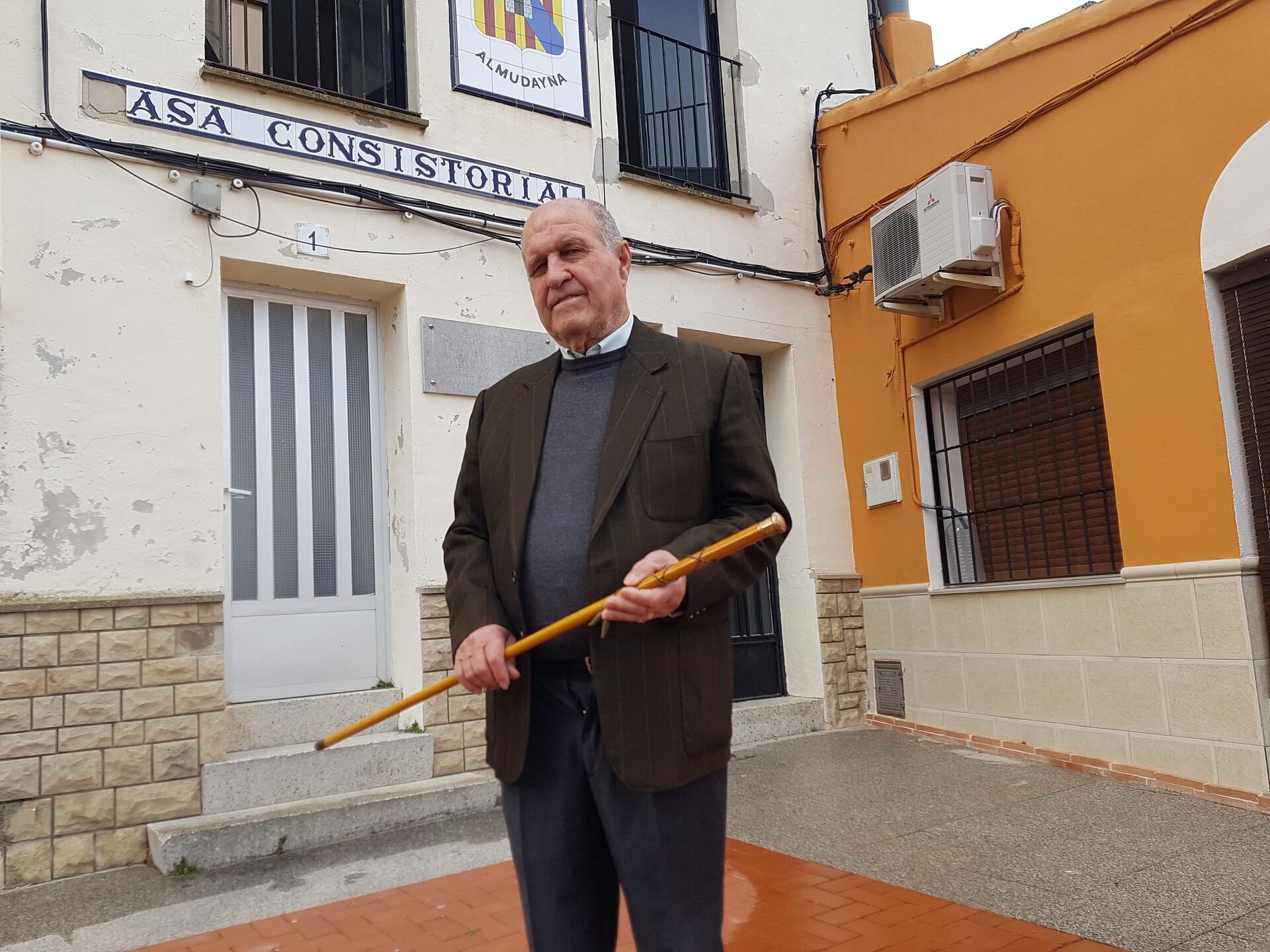 José Luis Seguí delante de la Casa Consistorial y la vara de mando con la que tomó posesión hace 51 años.