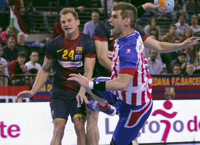 El pivote del Atlético de Madrid Julen Aginagalde ejecuta un lanzamiento ante el jugador eslovaco del Intersport Barcelona Martin Stranovsky  durante la primera semifinal de la XXXVIII Copa del Rey de Balonmano, que se disputa en el Palacio de los Deporte