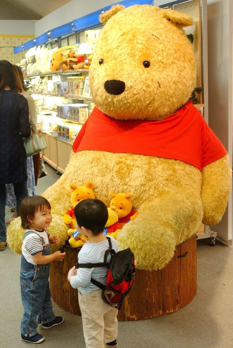 Dos niños observan en peluche gigante de Winnie the Pooh en una exhibición en Tokyo.