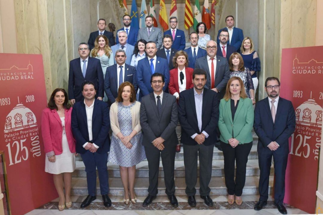 La actual Corporación Provincial posa en la escalinata del Palacio, sede de la Diputación junto a la imagen conmemorativa del aniversario