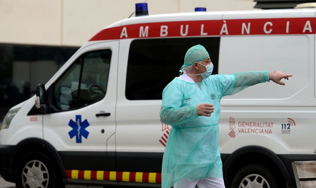 Un profesional sanitario, con un equipo de protección individual, frente a una ambulancia en el hospital La Fe de València. 