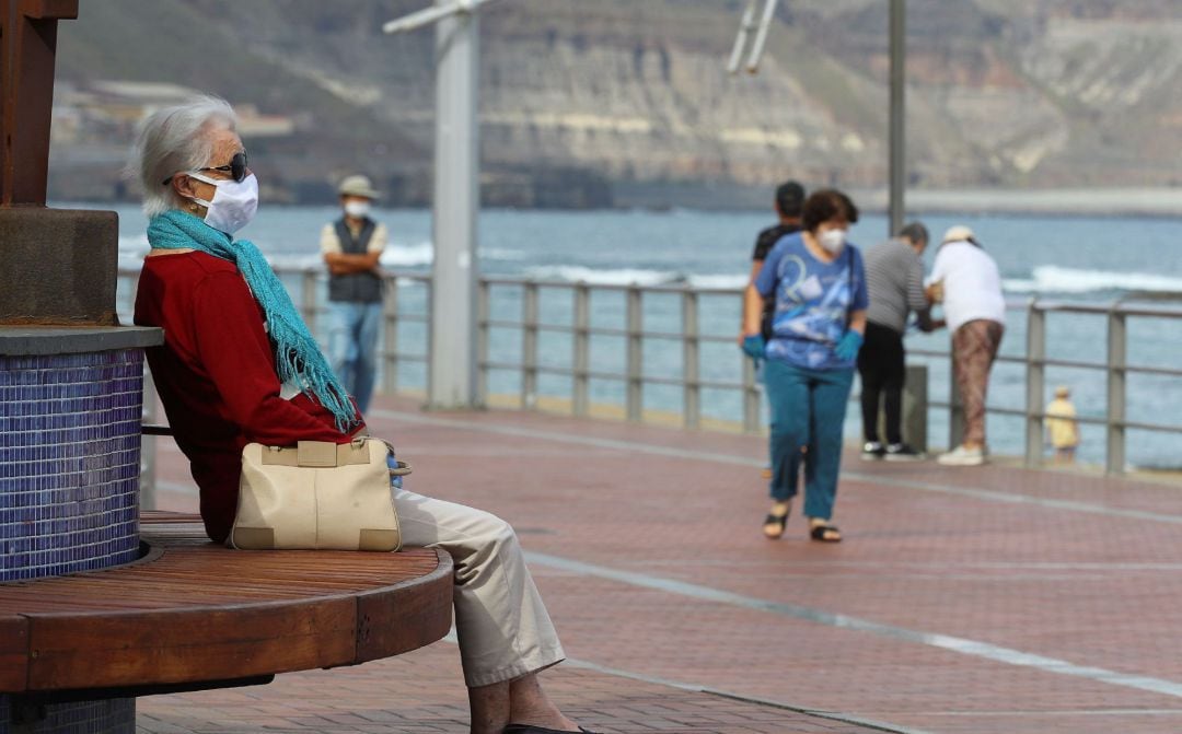 Varias personas mayores caminan por el paseo de la playa de Las Canteras 