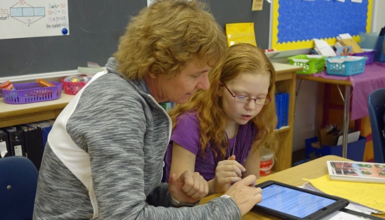 Una profesora ayuda a una estudiante que realiza actividades en una tableta en Wellsville, Nueva York.