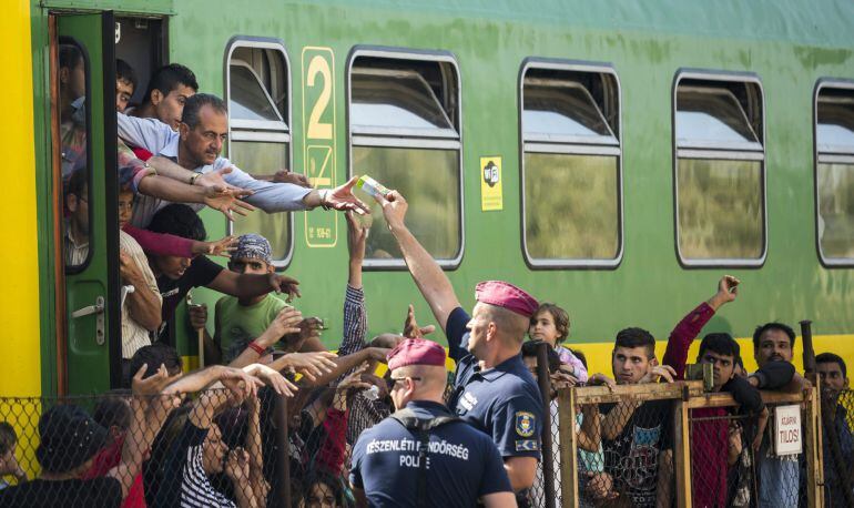 HUN09 BICSKE (HUNGRÍA) 04/09/2015.- Policías distribuyen zumos y fruta a los refugiados que permanecen varados en la estación ferroviaria de Bicske (Hungría)