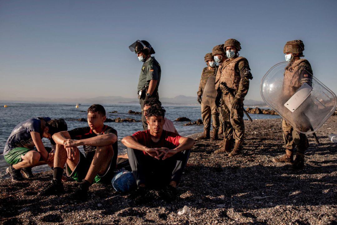 Miembros del ejército observan a un grupo de inmigrantes menores a su llegada a la playa de El Tarajal en Ceuta este miércoles. 