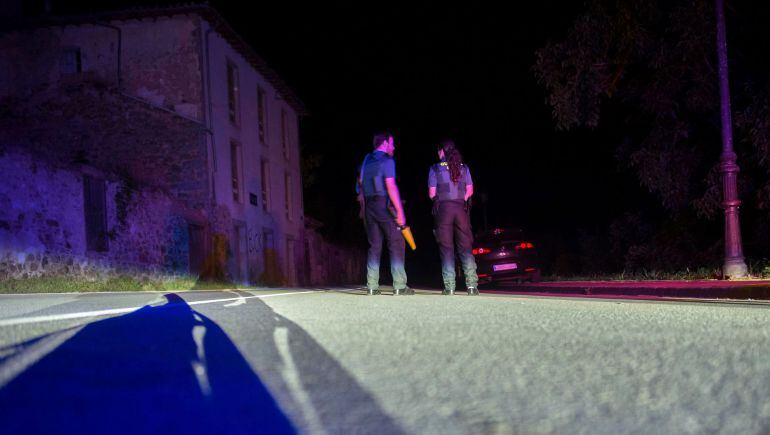 Dos agentes de la Guardia Civil cortan la carretera que da acceso al lugar en el que un hombre lleva atrincherado desde las 21.00 horas de hoy en una casa de Turieno, en el municipio cántabro de Camaleño, desde la que ha realizado varios disparos a la Guardia Civil.