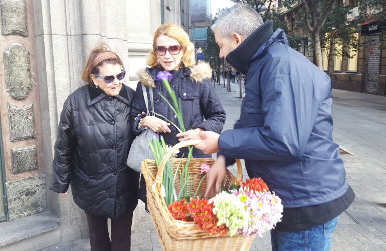 Un empleado de la compañía funeraria reparte flores a dos mujeres en la Gran Vía, esquina con la calle Fuencarral de Madrid.