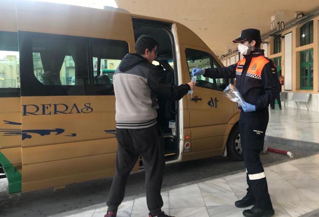 Un miembro de Protección Civil entrega una mascarilla a un usuario de transporte público en la estación de autobuses de la capital.