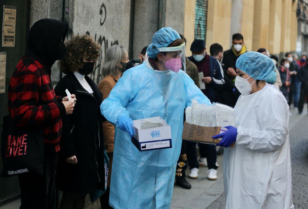 Dos sanitarias recogen test de Covid-19 de las personas que hacen cola en el Centro de Salud Universidad, a 21 de diciembre de 2021, en Madrid.