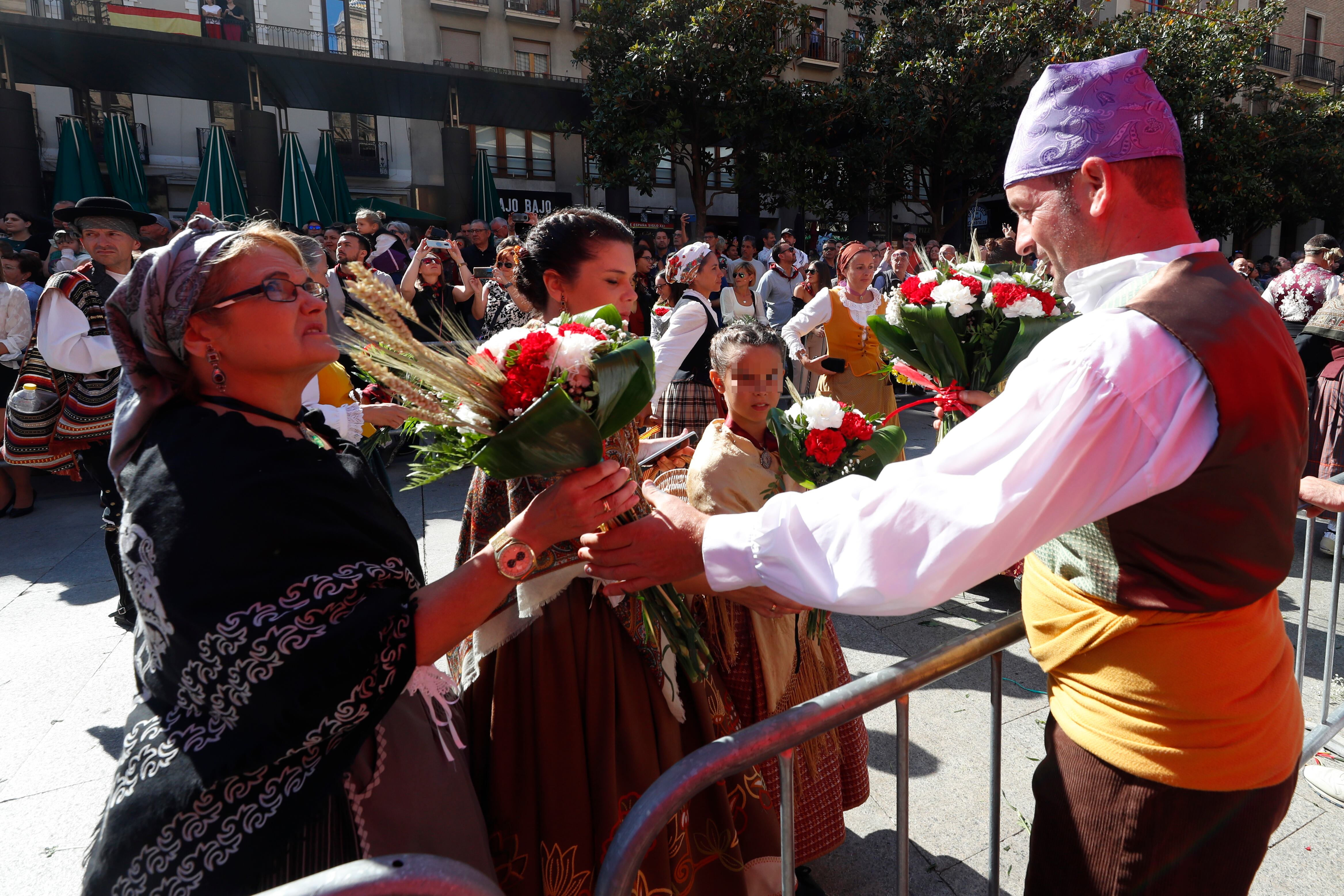 ZARAGOZA, 12/10/2022.- Varias personas entregan flores para decorar la imagen de la Virgen del Pilar que en una estructura levantada en el centro de la plaza de Zaragoza que lleva su nombre, una ofrenda llena de ilusión que se espera de récord tras dos años de pandemia, con más grupos inscritos que en 2019 y la previsión de alcanzar alrededor de siete millones de flores. EFE/ Javier Cebollada
