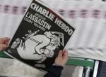 An employee of a printing house holds a copy of the latest edition of French weekly newspaper Charlie Hebdo with the title &quot;One year on, The assassin still on the run&quot; near Paris, France, January 4, 2016. France this week commemorates the victims of last 