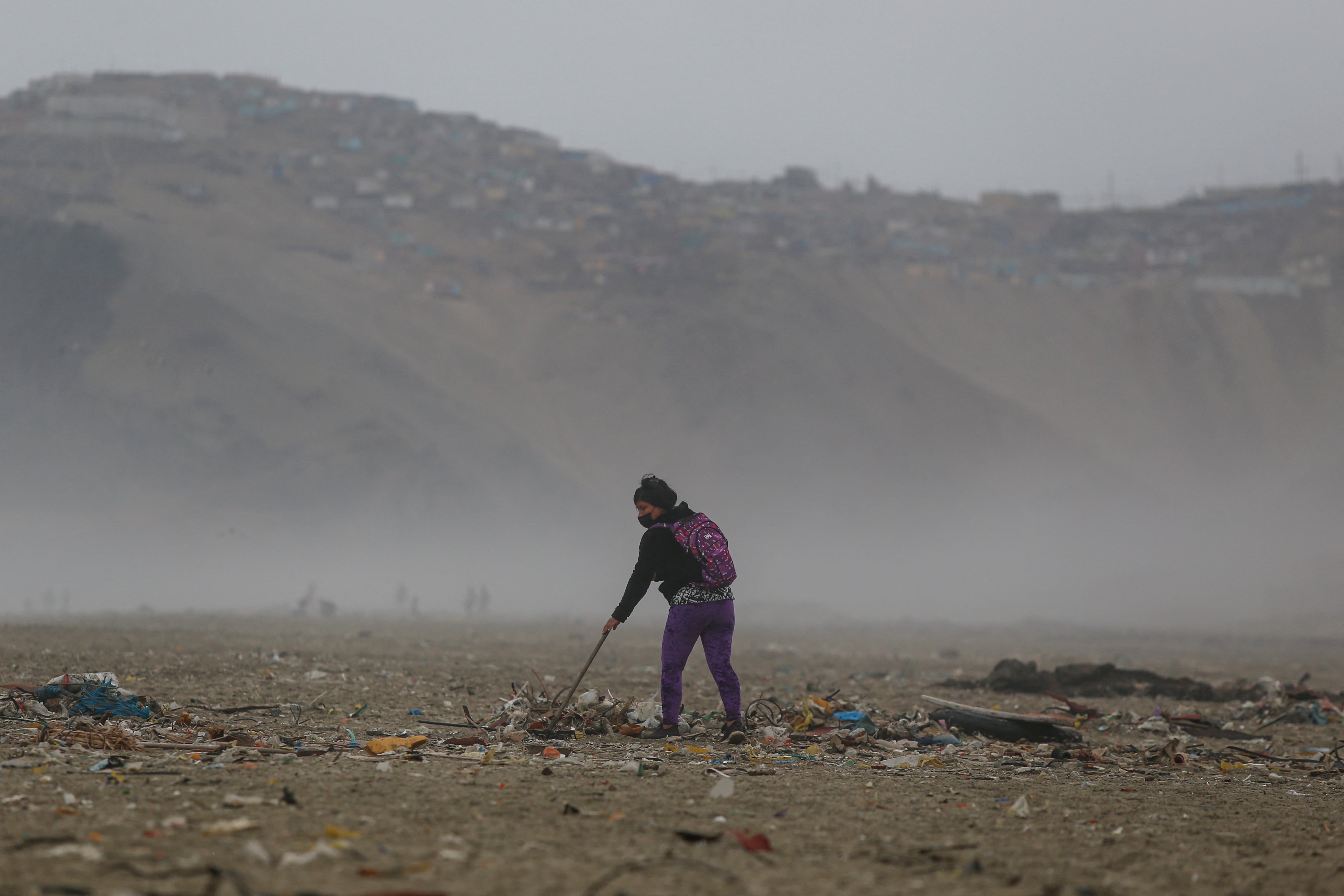 A woman cleans the shore of Cavero Beach, which was affected by an oil spill that occurred on January 15 and involved Spanish energy giant Repsol, in Pachacutec, an area on the northern outskirts of Lima, on July 09, 2022. - Described as an &quot;ecological disaster&quot; by the Peruvian government, the spill occurred while the Italian-flagged tanker &quot;Mare Doricum&quot; was unloading crude oil at the La Pampilla refinery in Ventanilla, owned by the Spanish oil company Repsol. The company attributed the fact to the agitation of the sea by a volcanic eruption in Tonga, on the other side of the Pacific. (Photo by Gian Masko / AFP) (Photo by GIAN MASKO/AFP via Getty Images)