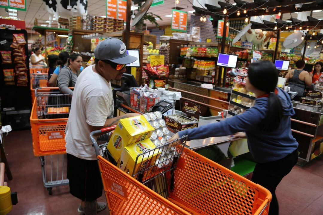 Una persona carga cervezas en un supermercado. 