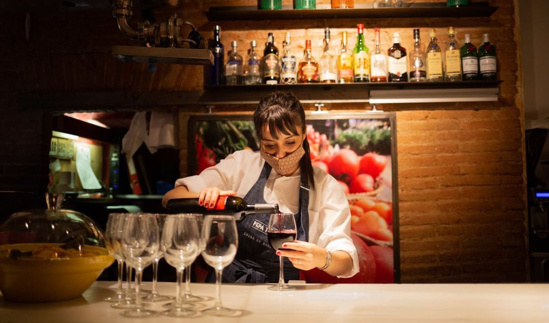 Una camarera sirve una copa de vino en el interior de un bar.