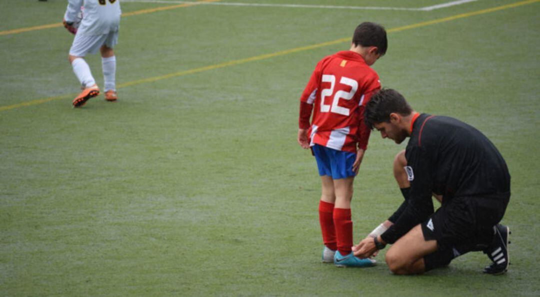 Un árbitro ayuda a un niño en el fútbol base