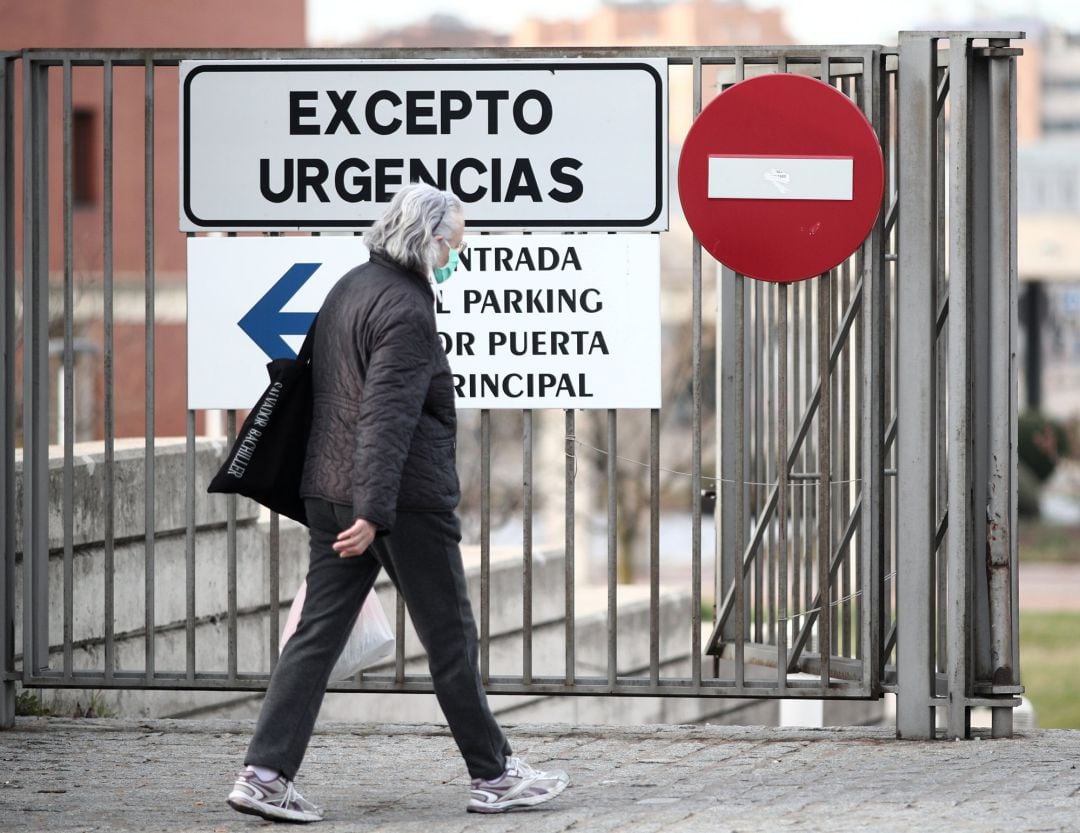 Una mujer protegida con mascarilla ante el avance del coronavirus pasea cerca de la puerta de Urgencias del Hospital Universitario Fundación de Alcorcón.